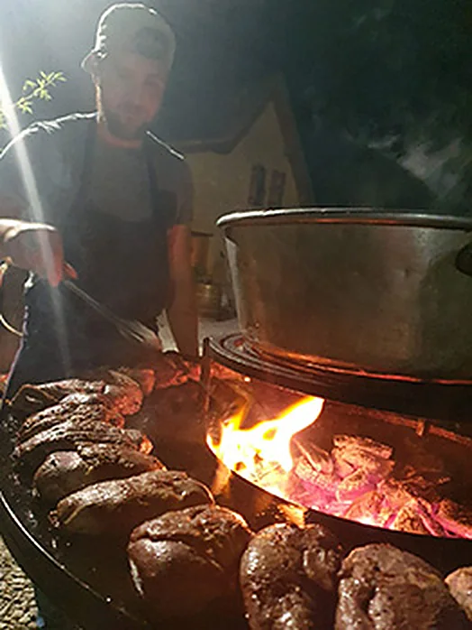 Cuisson au brasero à la tombée de la nuit, flammes sous la plaque