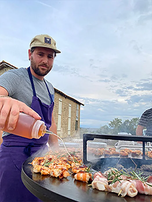 Nicolas Fort assaisonne gambas et brochettes sur la plancha du brasero, en extérieur