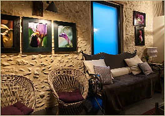 Coin salon du restaurant, murs en pierre et galets apparents, fauteuils en rotin