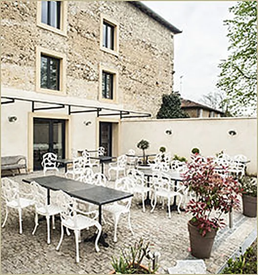 La terrasse du restaurant au pied de la façade en pierre de l'ancien chai